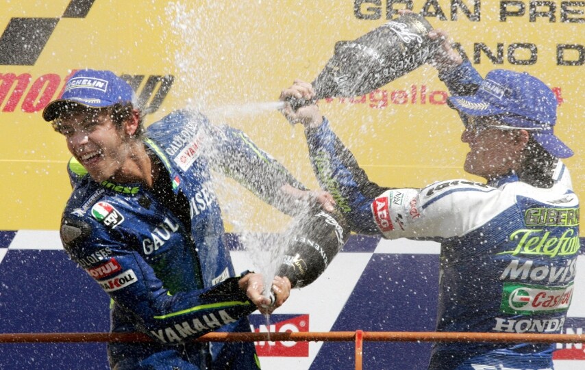 Valentino Rossi sul gradino più alto del podio al suo terzo trionfo consecutivo su circuito toscano, il quinto in carriera, davanti a Sete Gibernau e Max Biaggi. Gp d’Italia, Mugello 2004.