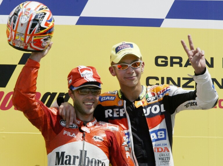 Valentino Rossi sul gradino più alto del podio al suo secondo trionfo consecutivo su circuito toscano, davanti a Loris Capirossi e Max Biaggi. Gp d’Italia, Mugello 2003.