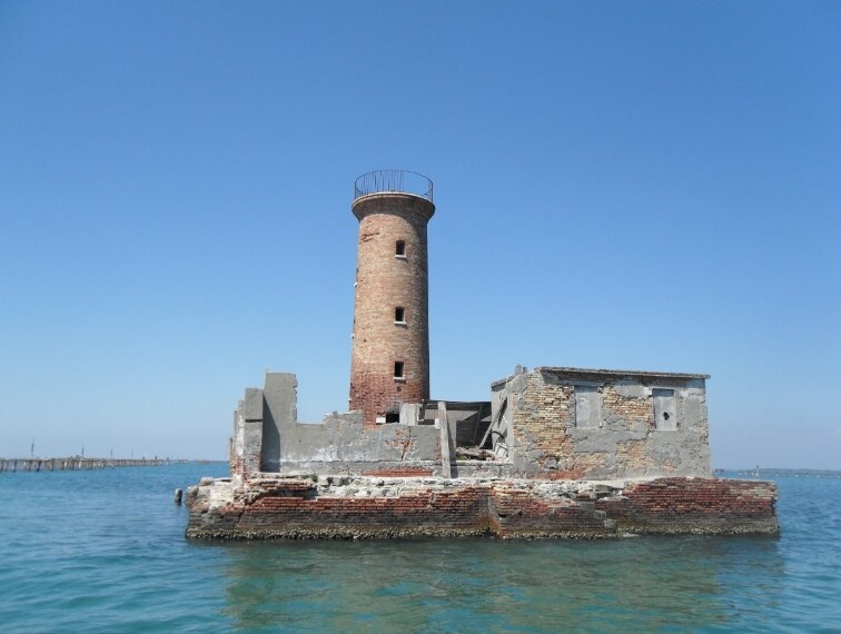 Si trova sull’Isola Spignon, piccola isola (circa 190 mq nominali) della Laguna Sud di Venezia, in Veneto. Il faro costruito nella seconda metà dell’800 è alto 15 metri e serviva per segnalare alle imbarcazioni l’entrata dal porto di Malamocco; il segnale luminoso intermittente era visibile ad una distanza di circa 9 miglia nautiche.