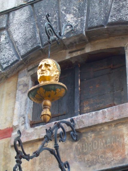 Una singolare testa d'oro può cogliere di sorpresa chi alza lo sguardo verso destra ai piedi del Ponte di Rialto dalla parte di S. Bartolomeo. La scultura bronzea sospesa nel vuoto è l'antica insegna della Spezieria “Alla Testa d'oro”: in un'epoca in cui pochi sapevano leggere, doveva essere ben visibile e riconoscibile da chiunque. Si riteneva che qui si producesse la migliore Theriaca della città, una sorta di rimedio universale ritenuto in grado di curare tutti i mali.