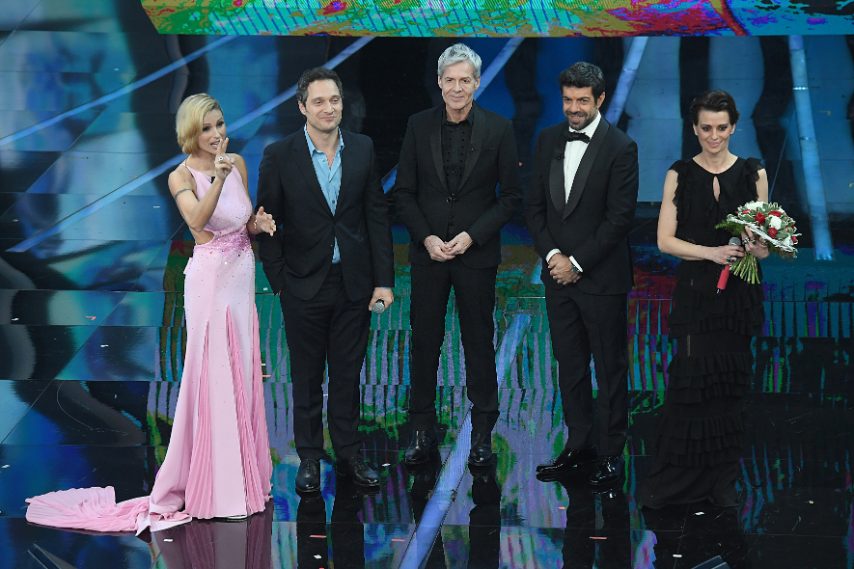 Giacca blu e camicia azzurra per lui, lungo abito nero pieno di ruche per lei