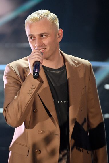 Il cantante con il cappotto e maxi maglietta che sembra un vestito