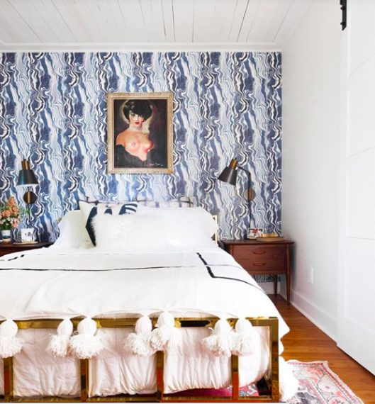 Puntare l'attenzione sulla parete decorandola con carta da parati o altre tecniche può essere uno stratagemma per far sembrare la camera più grande.