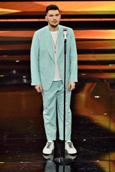 Il giovane cantante delle nuove proposte indossa per la serata un completo color pastello su shirt bianca