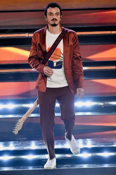 Il cantante indossa un completo color ruggine su shirt a stampa