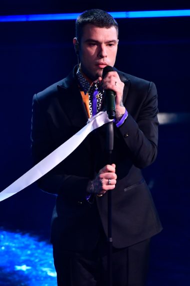 Il rapper indossa un completo scuro su camicia dalla stampa colorata