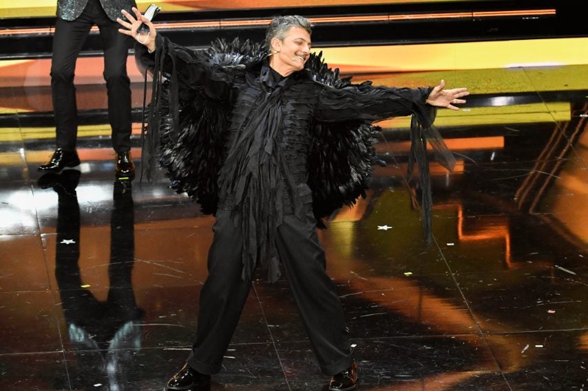 Il conduttore appare sul palco con sulle spalle una particolare impalcatura ricoperta di piume nere, imitando Achille Lauro