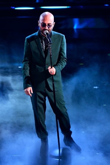 Il cantante sceglie per il palco un completo verde bottiglia e camicia a stampa