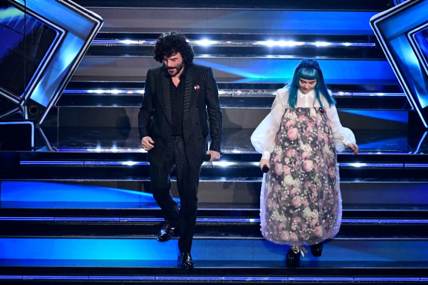 Abito doppio petto gessato con bordino e bottoni ricoperti in faille, camicia in popeline nero e stivaletti neri per il cantante