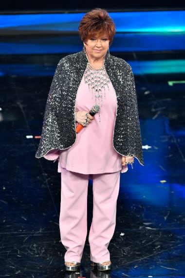 La cantante sceglie un look rosa pastello con mantella luccicante