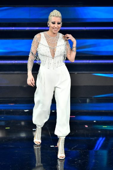 Total white per la cantante che sceglie un outfit con decoro gioiello sulle spalle