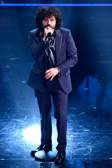 Uno smoking blu dai rever a lancia caratterizza il look del cantante