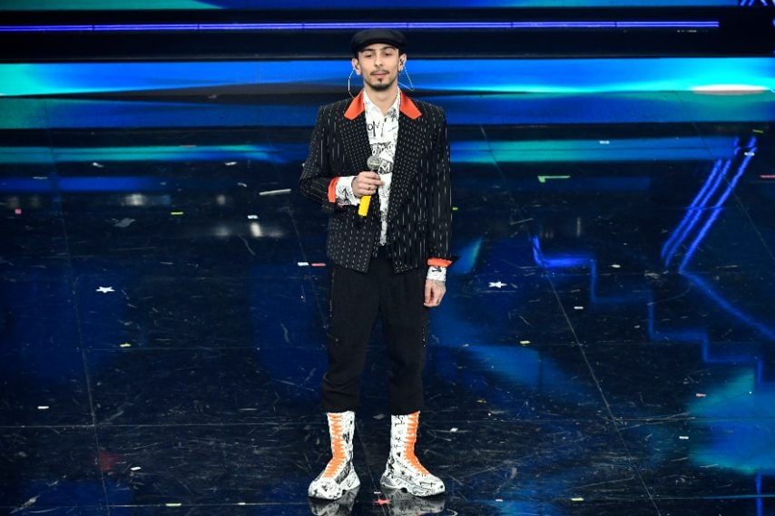 Giacca gessata su camicia e sneakers graffiti per il cantante sul palco