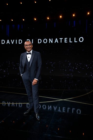 Il conduttore indossa un completo tre pezzi blu navy e scarpe stringate Salvatore Ferragamo